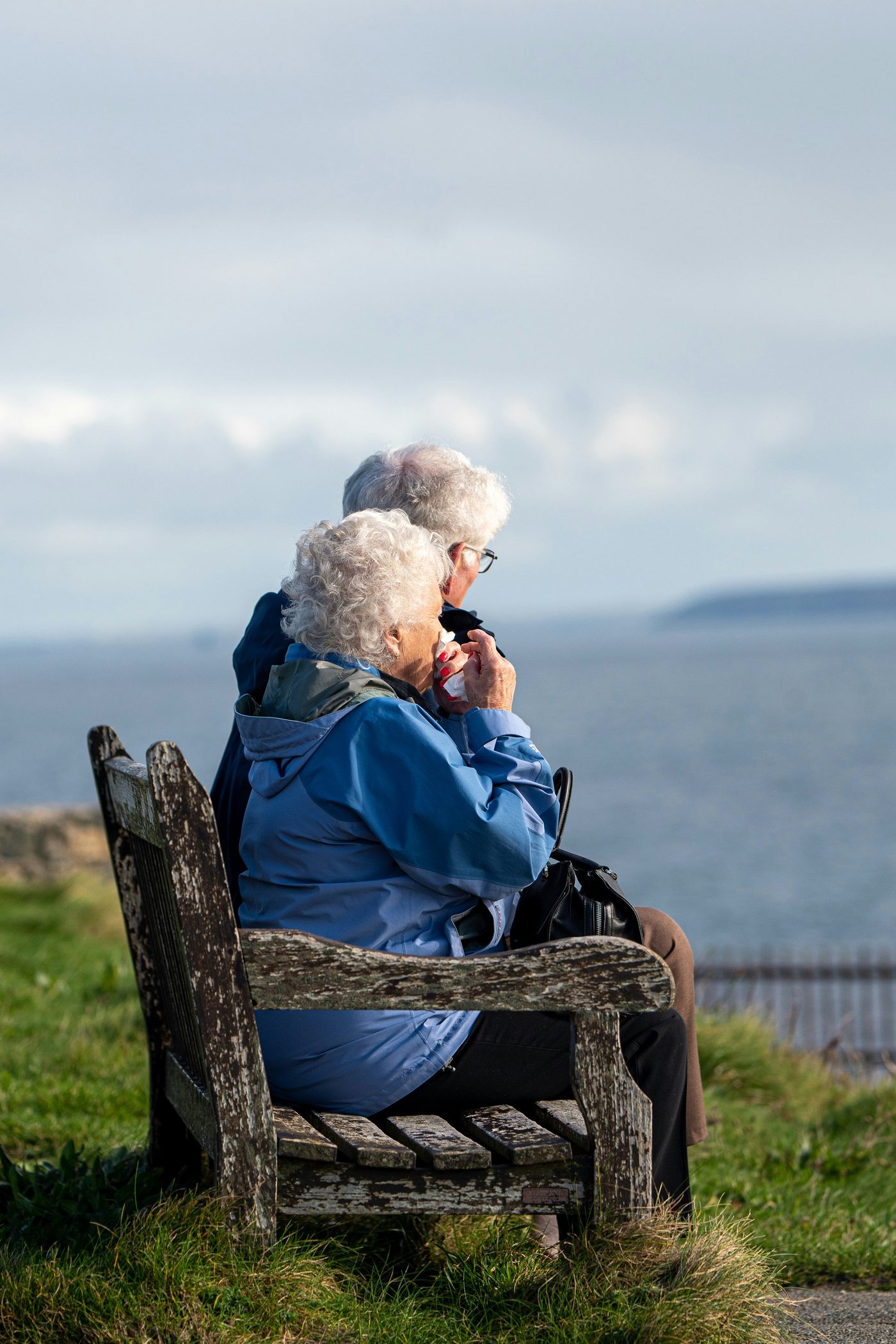An older couple sitting together by the sea